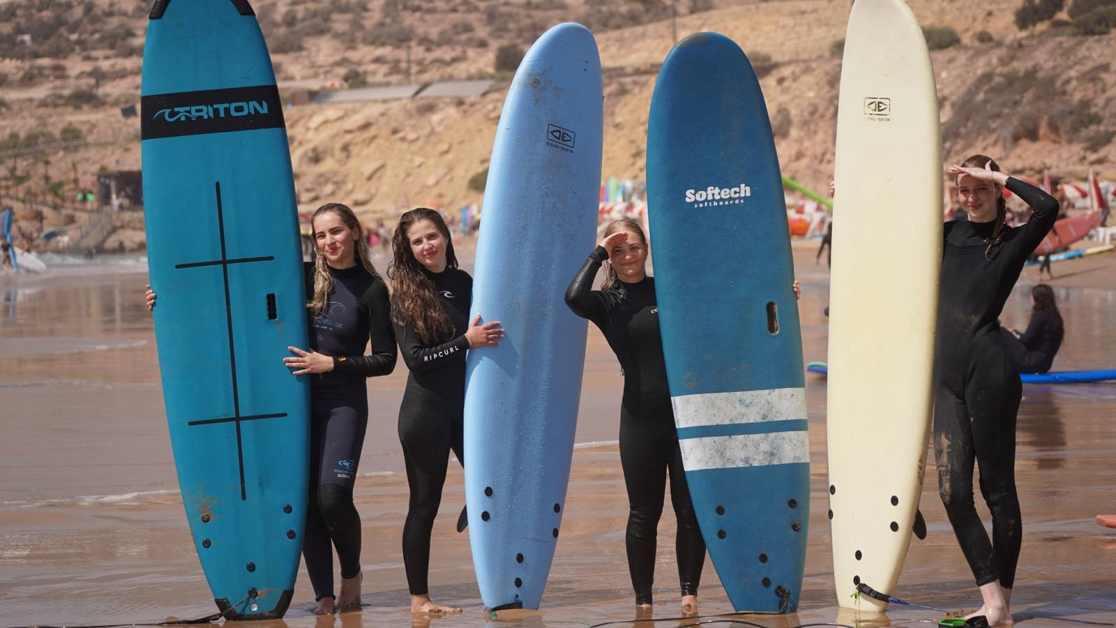 A local surf instructor teaching technique on the beach during a beginner surf lesson in Taghazout