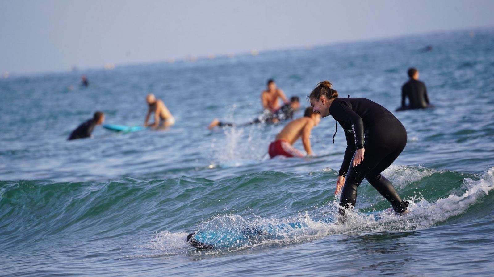 Élève de surf qui rit en surfant une vague à Taghazout