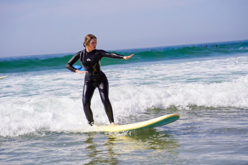 Beginner surfer riding a whitewater wave on a soft-top board in Taghazout