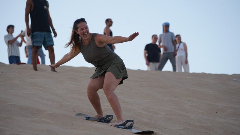 Woman laughing as she sandboards down the Timlaline dunes near Agadir