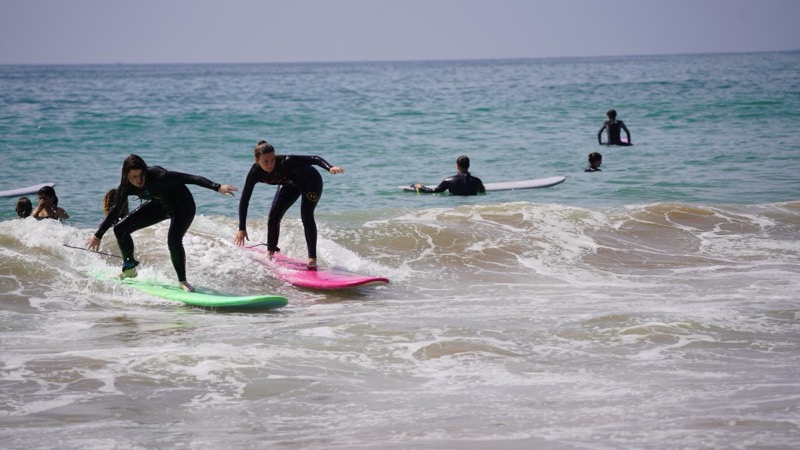 Two beginners riding whitewater side by side on soft-top boards