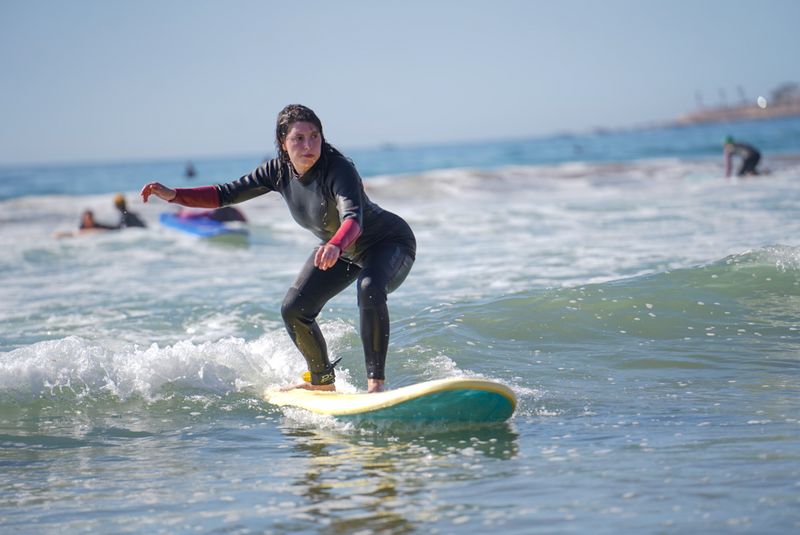 Surfer catching a wave during a surf lesson in Taghazout, a popular Morocco surf holiday destination for UK visitors