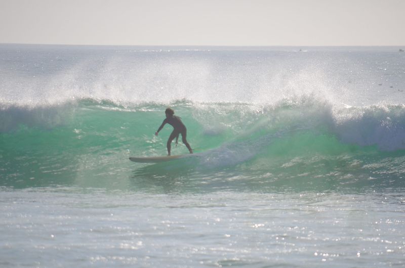 Surfer carrying a board on the beach in Taghazout, Morocco, a popular surf holiday spot for UK travellers