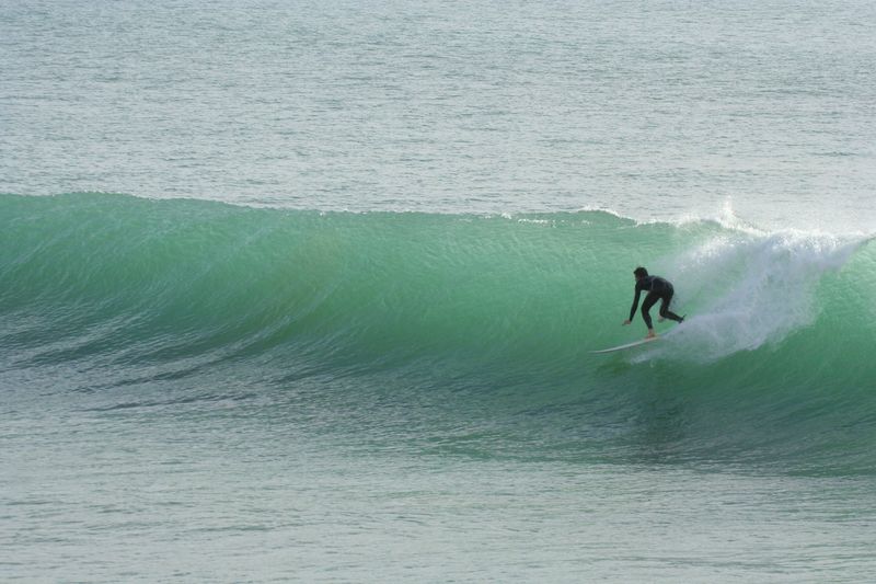 A surfer riding a large clean wave at Killer Point in Taghazout, a rock-bottom point break that is not suitable for beginners