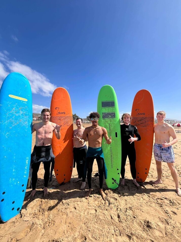 Surf instructor with happy beginner students after completing a surf lesson in Taghazout, Morocco